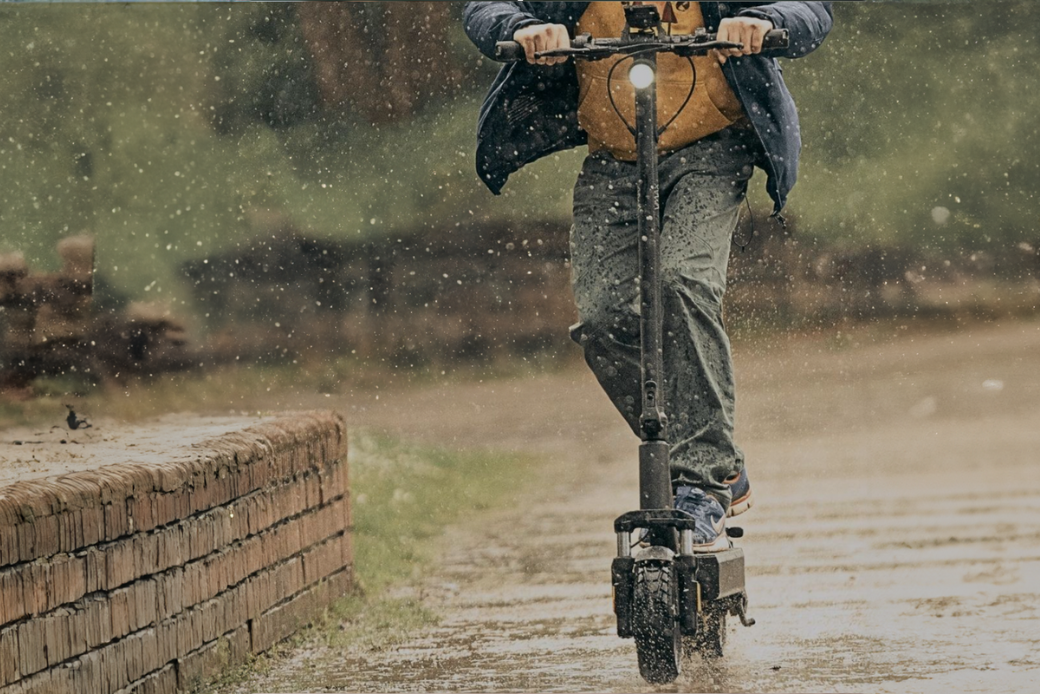 Ein Bild von einem Mann, der einen VMAX E-Scooter auf einem verregneten Weg fährt